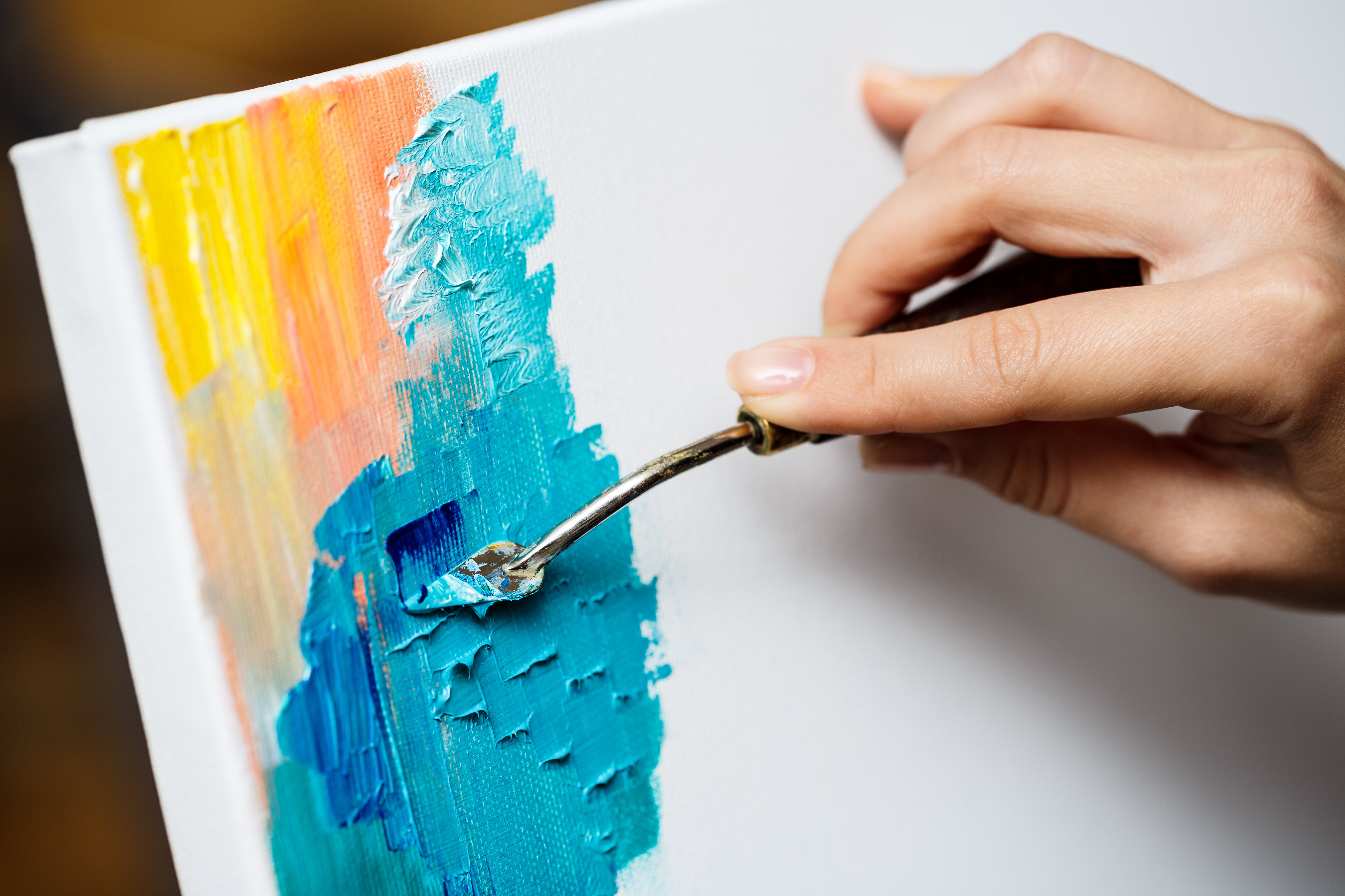 Close up of girl drawing with oil paints on canvas.