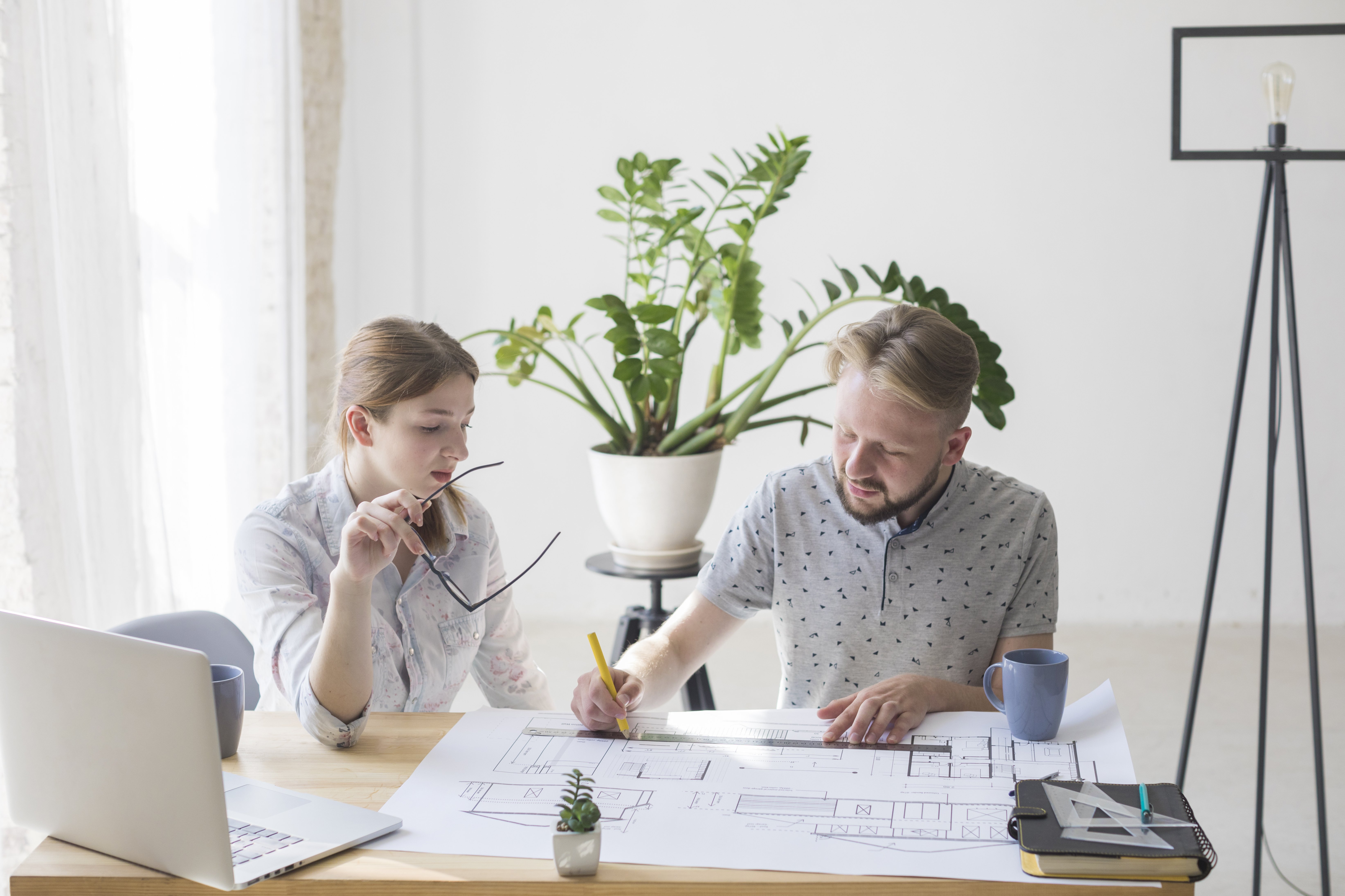 pretty-woman-looking-blueprint-while-her-colleague-working-it